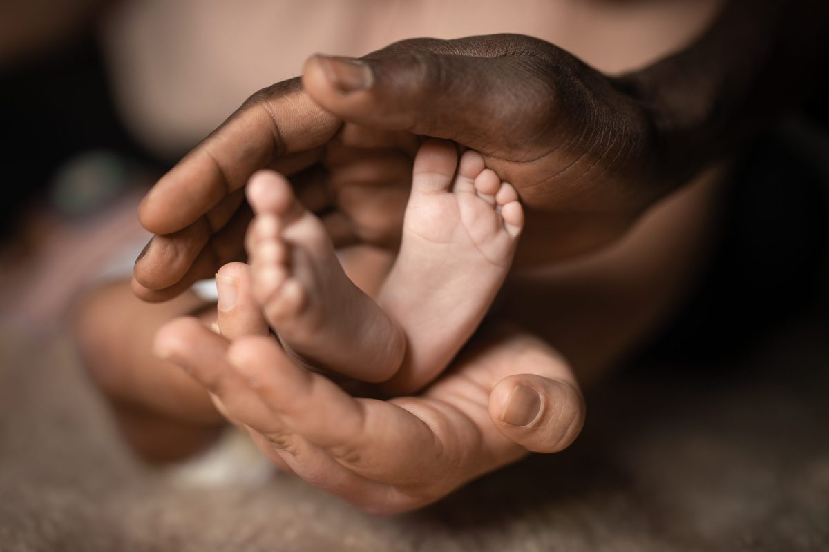 parents hands around babies feet