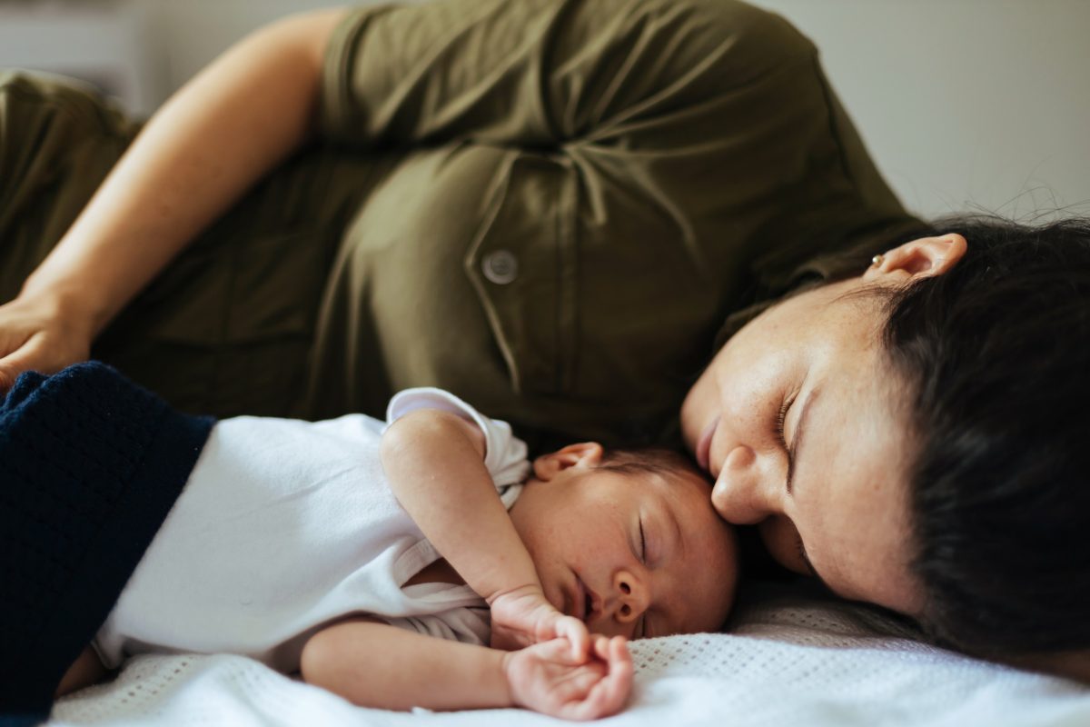mother kissing her sleeping babies forehead