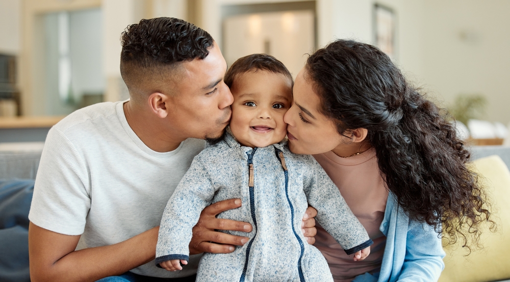 mom and dad kissing their infant