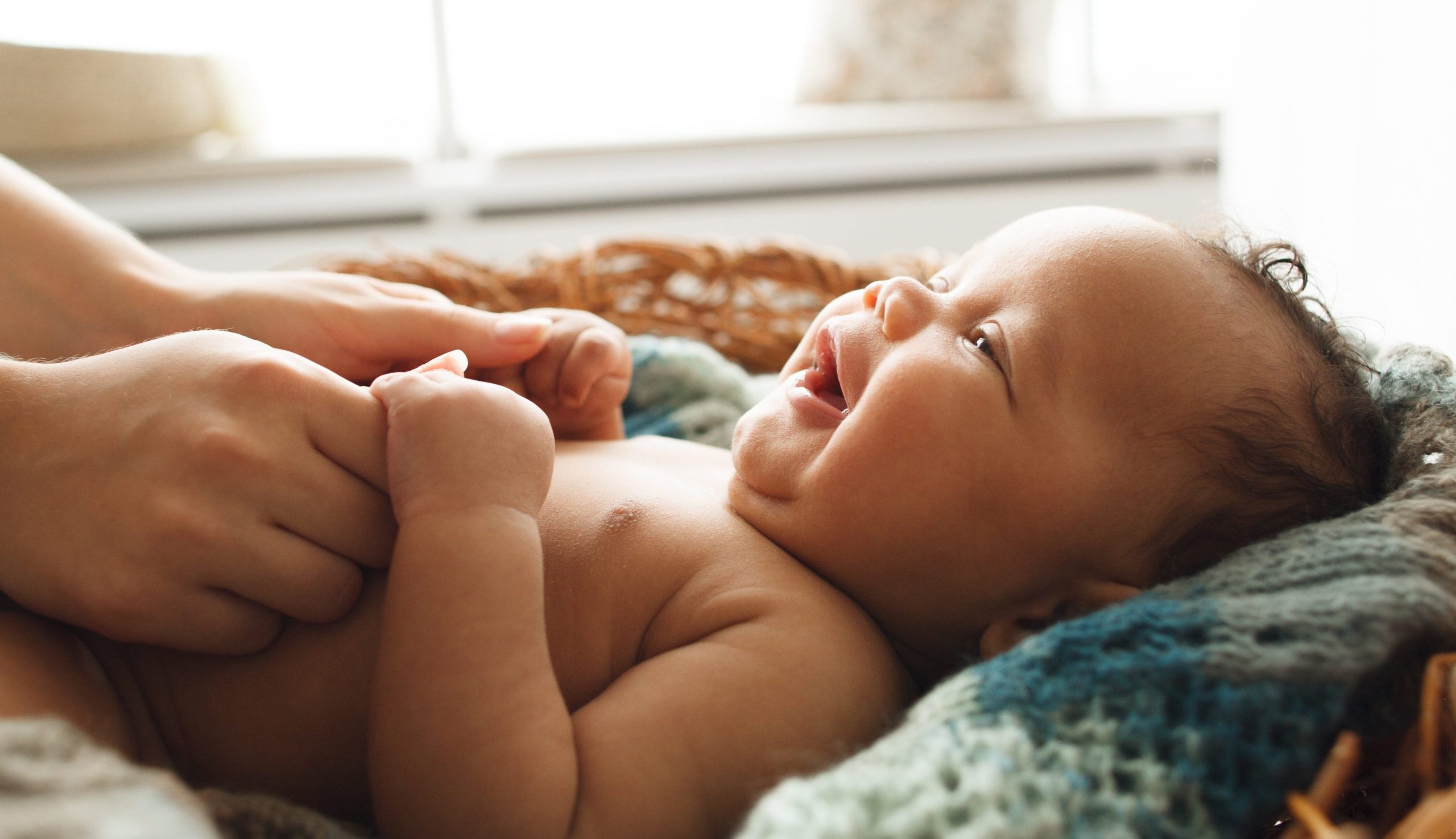 mothers hands on her laughing baby